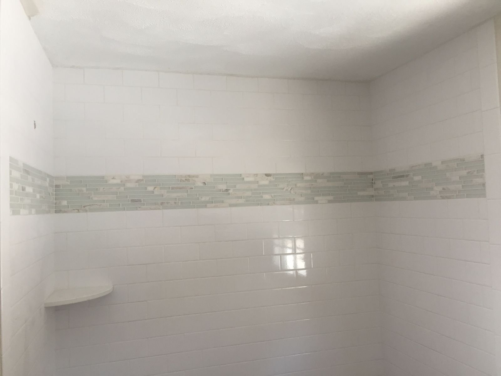 Tiled shower with a glass mosaic accent band