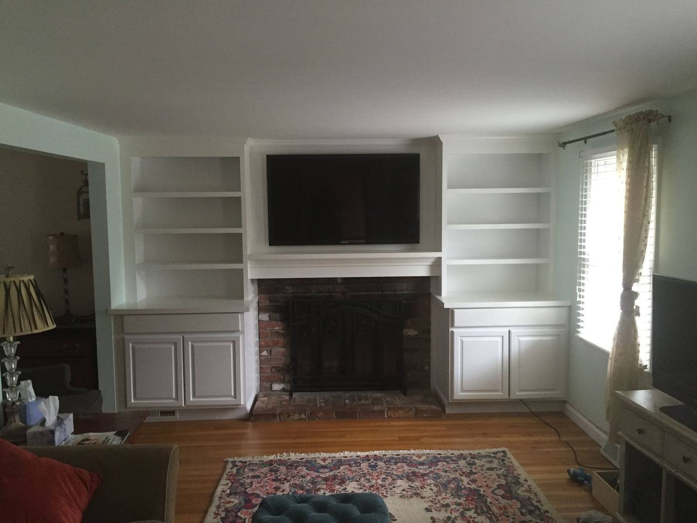 Built-in cabinets and shelving flanking a brick fireplace