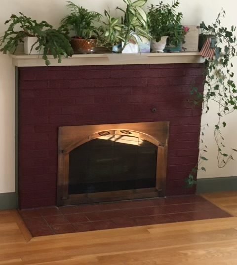 Original painted red brick fireplace with a wood mantel shelf